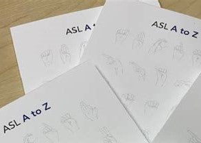 Three American Sign Language (ASL) Note Paper Pads with ASL A to Z printed across the top of the page.  ASL alphabet printed faintly in the background and Deaf and Hear Alberta printed across the bottom of the page.