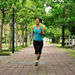 A woman jogs along a brick pathway wearing a teal tank top and leggings.  She uses the Phonak Stick 'n' Stay Hearing Aid Stickers (30 pair) 098-0353 Adhesives so that her hearing aid and Cochlear implant do not fall off and get lost while she is running. 