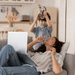 Serenity Choice Reusable Hearing Protection can be used in many situations.  In this photo a mother is laying on the couch with her laptop holding her pointer finger to her lips as she looks at her young son.  The son is holding a metal pot lid and ladle above his head making loud noise.  