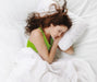 A woman lays in bed sleeping soundly.  She is a regular user of the Serenity Choice Reusable Hearing Protection for SLEEP Earplugs.